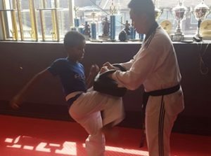 A dedicated instructor providing one-on-one Taekwondo training and youth self-defense coaching in a professional studio setting.