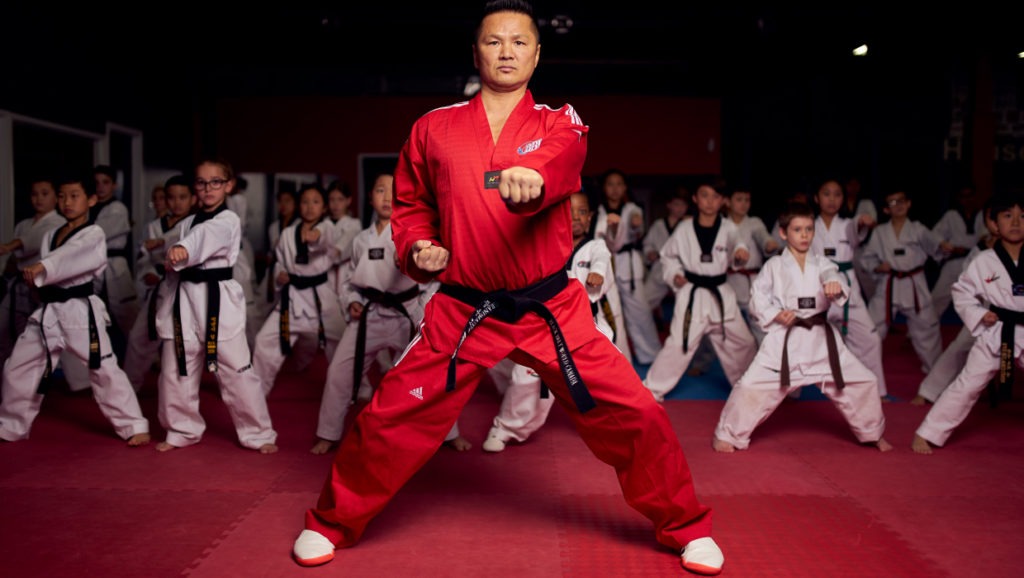 A high-ranking master performing a lead punch during a black belt class to demonstrate perfect martial arts technique.