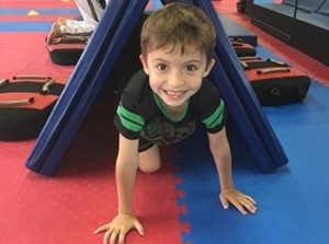 Young students practicing coordination exercises on a red mat during a youth fitness class to improve gross motor skills.