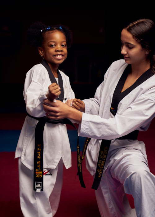 A young student receiving expert guidance on a self-defense technique to improve child development and coordination.