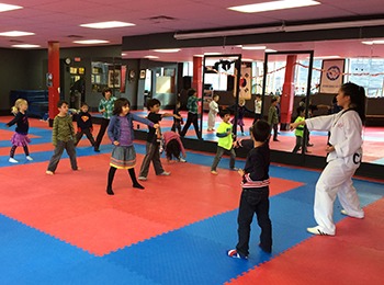 Students participating in taekwondo agility drills on professional martial arts mats to improve reaction time.
