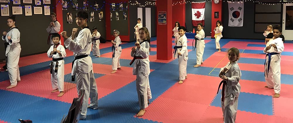 A diverse group of young students practicing stances in a professional karate for kids studio to improve youth fitness.